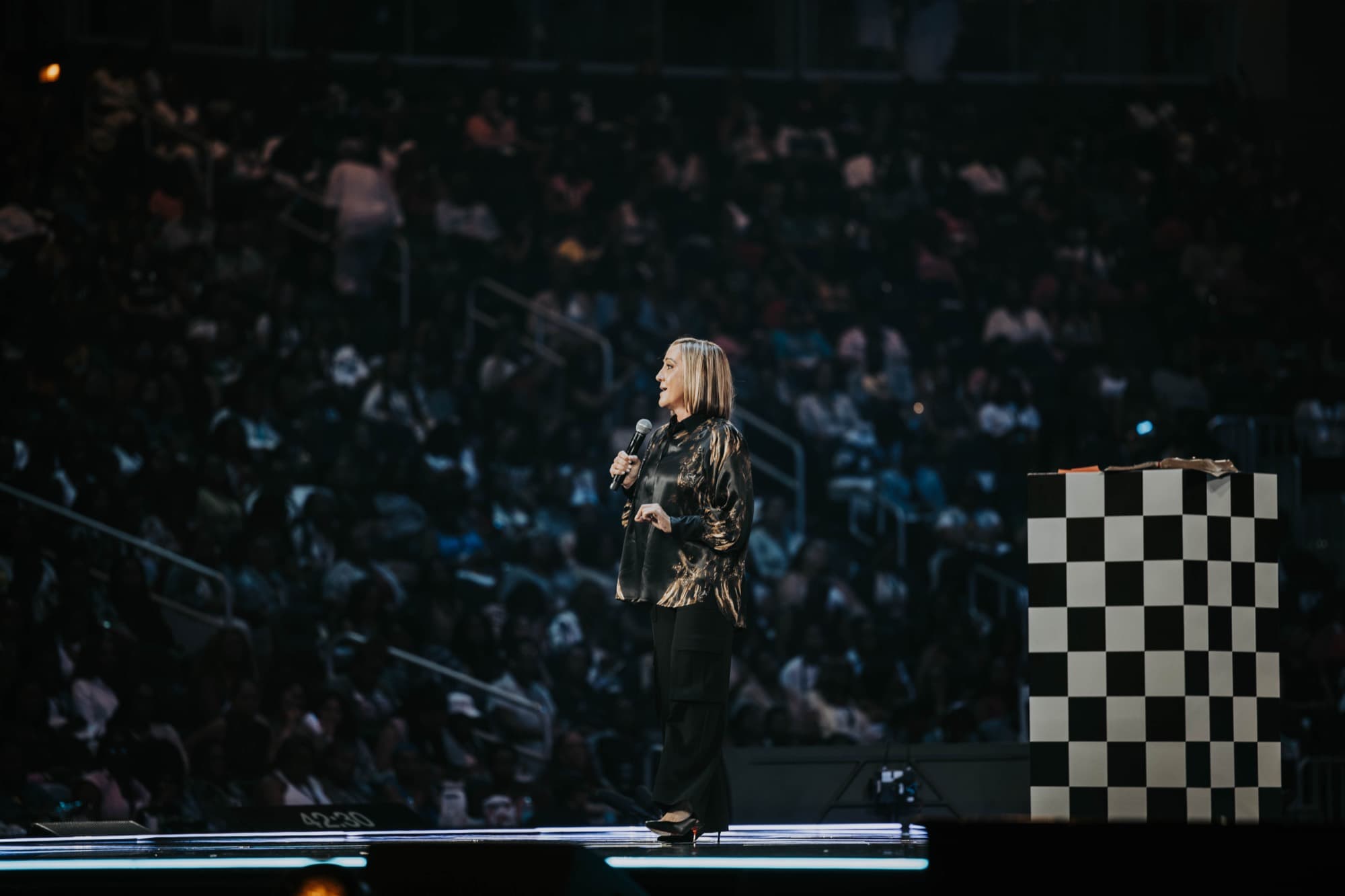 A Woman Evolve 2025 speaker on stage above a packed arena crowd